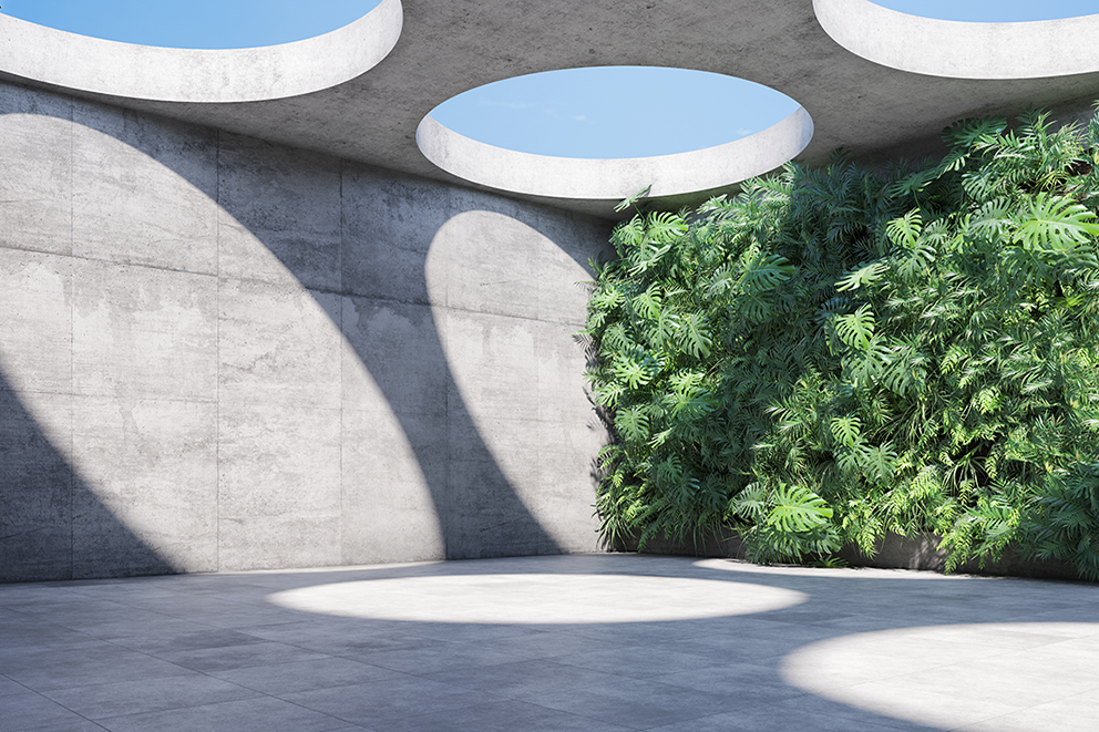 Innenhof mit Betonwänden und kreisförmigen Lichtöffnungen, grüne Pflanzenwand.