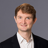 Lukas Felber in formeller Kleidung vor neutralem Hintergrund.
