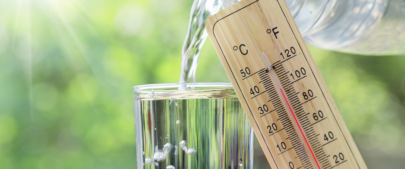 Thermometer zeigt hohe Temperaturen. Daneben Darstellung eines Wasserglases.