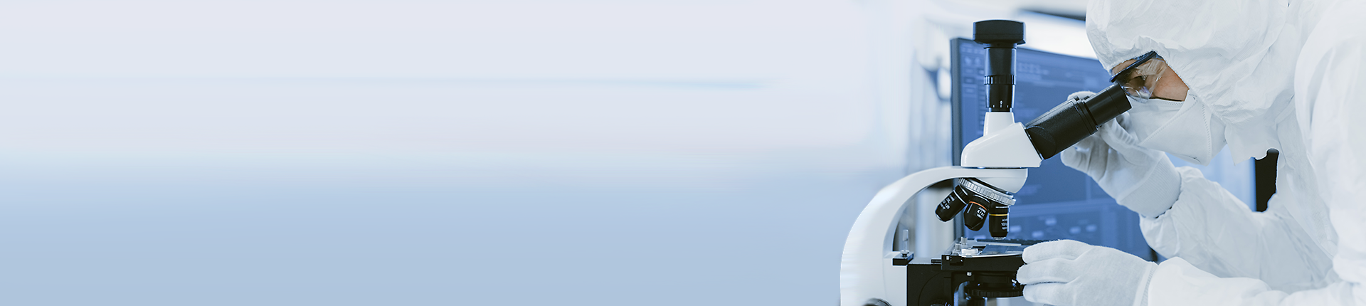 Wissenschaftler in Schutzkleidung, der im Labor mit einem Mikroskop forscht. 